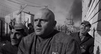 Movie still from “The Pawnbroker” (1964), directed by Sidney Lumet – A man with a bald head is standing in front of a group of people; Close Up shot, Over the shoulder angle