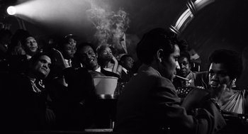 Movie still from “The Pawnbroker” (1964), directed by Sidney Lumet – A black and white photo of a group of people smoking; Medium shot, Over the shoulder angle