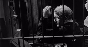 Movie still from “The Pawnbroker” (1964), directed by Sidney Lumet – A man sitting in front of a jail cell; Close Up shot, Low angle