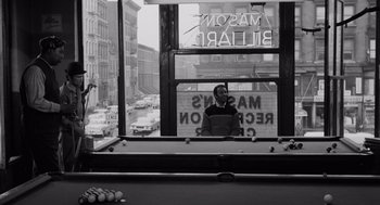 Movie still from “The Pawnbroker” (1964), directed by Sidney Lumet – A man standing in front of a pool table in front of a window; Wide shot, High angle