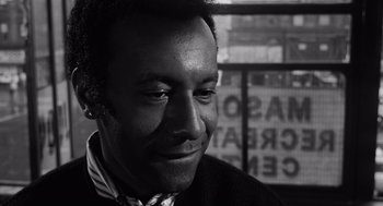 Movie still from “The Pawnbroker” (1964), directed by Sidney Lumet – A black - and - white photo of a man smiling at the camera; Close Up shot, Over the shoulder angle