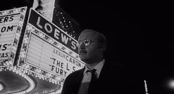 Movie still from “The Pawnbroker” (1964), directed by Sidney Lumet – A black and white photo of a man in front of a movie theater; Medium shot, Low angle