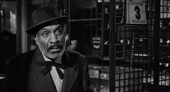 Movie still from “The Pawnbroker” (1964), directed by Sidney Lumet – An older man wearing a hat and a suit; Close Up shot, Over the shoulder angle