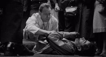 Movie still from “The Pawnbroker” (1964), directed by Sidney Lumet – A man is helping another man who is laying on the ground; Medium shot, High angle