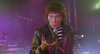 Movie still from “The Perfect Man” (2005), directed by Mark Rosman – A man in a leather jacket is holding a microphone; Medium shot, Low angle