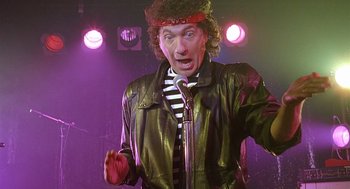 Movie still from “The Perfect Man” (2005), directed by Mark Rosman – A man in a leather jacket is singing into a microphone; Medium shot, Low angle
