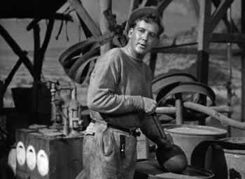 Movie still from “The Petrified Forest” (1936), directed by Archie Mayo – A man standing in front of an oven holding a pan; Medium shot, Low angle