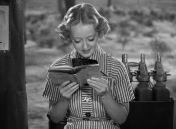 Movie still from “The Petrified Forest” (1936), directed by Archie Mayo – A woman is reading a book while sitting in a chair; Medium shot, High angle
