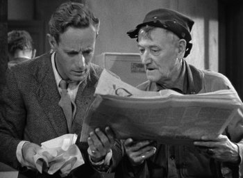 Movie still from “The Petrified Forest” (1936), directed by Archie Mayo – Two men are looking at a newspaper together; Close Up shot, Over the shoulder angle