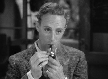 Movie still from “The Petrified Forest” (1936), directed by Archie Mayo – A black and white photo of a man smoking a pipe; Close Up shot, High angle