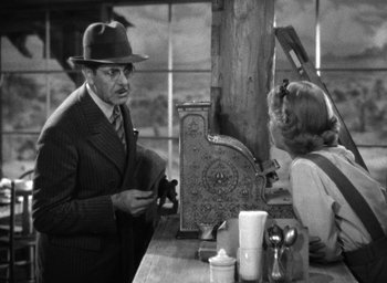 Movie still from “The Petrified Forest” (1936), directed by Archie Mayo – An old photo of a man and a woman at a table; Medium shot, Low angle
