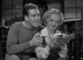 Movie still from “The Petrified Forest” (1936), directed by Archie Mayo – A man and a woman sitting on a couch looking at a book; Medium shot, Low angle