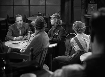 Movie still from “The Petrified Forest” (1936), directed by Archie Mayo – A group of people sitting around a wooden table; Medium shot, High angle