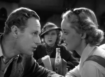 Movie still from “The Petrified Forest” (1936), directed by Archie Mayo – A man and a woman sitting in front of a woman; Close Up shot, Over the shoulder angle