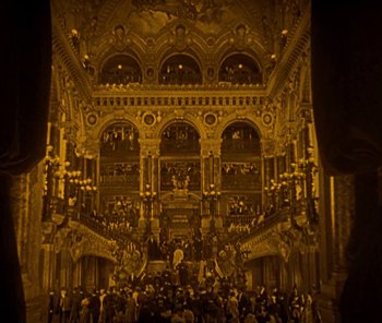 Movie still from “The Phantom of the Opera” (1925), directed by Lon Chaney – A group of people standing in front of an ornate building; Extreme Wide shot, High angle