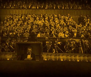 Movie still from “The Phantom of the Opera” (1925), directed by Lon Chaney – An orchestra is playing in front of a large crowd; Extreme Wide shot, High angle