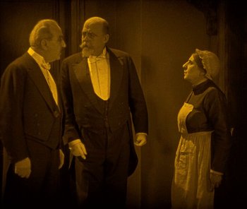 Movie still from “The Phantom of the Opera” (1925), directed by Lon Chaney – A group of three men standing next to each other; Medium shot, High angle