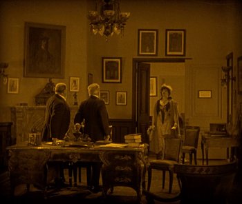 Movie still from “The Phantom of the Opera” (1925), directed by Lon Chaney – A group of people sitting at a table in a living room; Extreme Wide shot, High angle