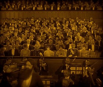Movie still from “The Phantom of the Opera” (1925), directed by Lon Chaney – A crowd of people sitting in a stadium; Extreme Wide shot, High angle