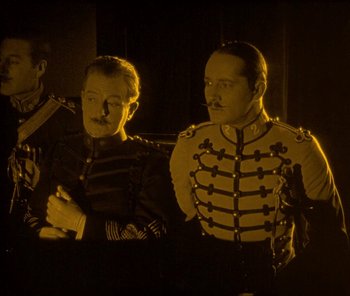 Movie still from “The Phantom of the Opera” (1925), directed by Lon Chaney – A couple of men standing next to each other in a room; Medium shot, High angle