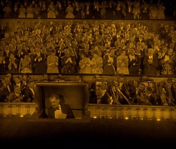Movie still from “The Phantom of the Opera” (1925), directed by Lon Chaney – A crowd of people sitting in front of an audience; Extreme Wide shot, High angle