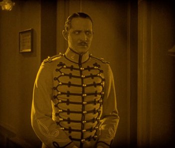 Movie still from “The Phantom of the Opera” (1925), directed by Lon Chaney – A man in a military uniform standing in front of a wall; Medium shot, High angle