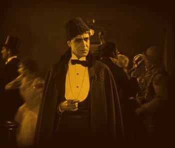 Movie still from “The Phantom of the Opera” (1925), directed by Lon Chaney – A man wearing a hat and a black coat; Medium shot, Low angle