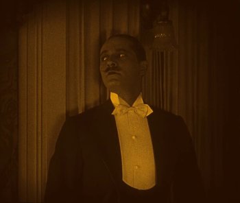 Movie still from “The Phantom of the Opera” (1925), directed by Lon Chaney – A man in a suit and bow tie looking to his left; Medium shot, Low angle
