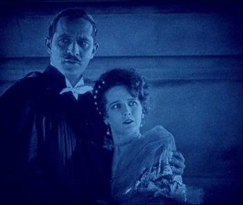 Movie still from “The Phantom of the Opera” (1925), directed by Lon Chaney – A man and a woman standing next to each other; Medium shot, High angle