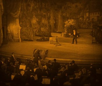 Movie still from “The Phantom of the Opera” (1925), directed by Lon Chaney – An audience is sitting in a theater watching a performance; Extreme Wide shot, High angle