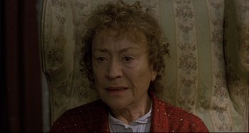 Movie still from “The Piano Teacher” (2001), directed by Michael Haneke – An older woman in a red jacket is looking at the camera; Close Up shot, High angle