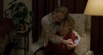 Movie still from “The Piano Teacher” (2001), directed by Michael Haneke – A woman hugging another woman while sitting in a chair; Medium shot, High angle
