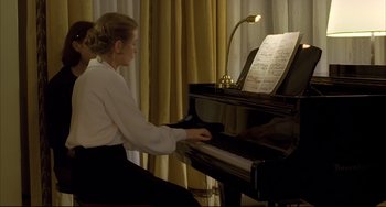 Movie still from “The Piano Teacher” (2001), directed by Michael Haneke – A woman sitting at a piano with a sheet of music; Medium shot, Low angle