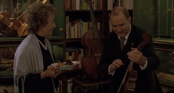 Movie still from “The Piano Teacher” (2001), directed by Michael Haneke – A man and a woman are standing in front of a violin; Medium shot, Over the shoulder angle