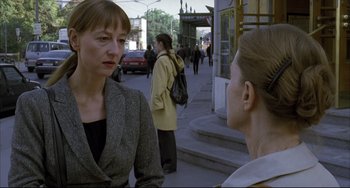 Movie still from “The Piano Teacher” (2001), directed by Michael Haneke – Two women on the sidewalk of a busy street; Medium shot, Over the shoulder angle