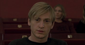 Movie still from “The Piano Teacher” (2001), directed by Michael Haneke – A man with blonde hair is looking at the camera; Close Up shot, Low angle