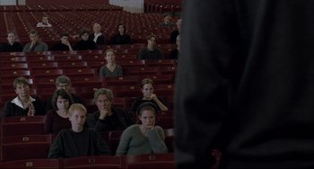 Movie still from “The Piano Teacher” (2001), directed by Michael Haneke – A group of people sitting in rows in a theater; Wide shot, High angle