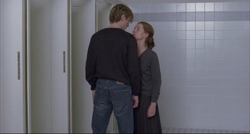 Movie still from “The Piano Teacher” (2001), directed by Michael Haneke – A man and a woman standing next to each other in front of a tiled wall; Medium shot, Over the shoulder angle