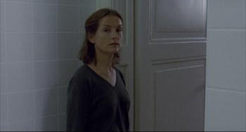 Movie still from “The Piano Teacher” (2001), directed by Michael Haneke – A woman standing in front of a white door; Medium shot, Over the shoulder angle
