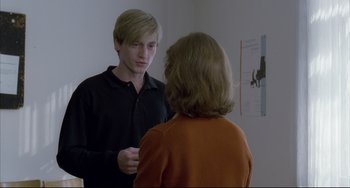 Movie still from “The Piano Teacher” (2001), directed by Michael Haneke – A man and a woman looking in the same mirror; Medium shot, Over the shoulder angle