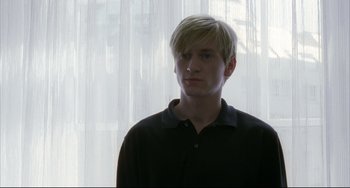 Movie still from “The Piano Teacher” (2001), directed by Michael Haneke – A man with blonde hair wearing a black shirt; Close Up shot, Over the shoulder angle