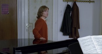 Movie still from “The Piano Teacher” (2001), directed by Michael Haneke – A woman standing in front of a mirror in front of a piano; Medium shot, Over the shoulder angle