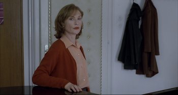 Movie still from “The Piano Teacher” (2001), directed by Michael Haneke – A woman standing in front of a mirror in a room; Medium shot, Over the shoulder angle