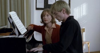 Movie still from “The Piano Teacher” (2001), directed by Michael Haneke – A man and a woman are playing a piano together; Medium shot, Over the shoulder angle