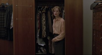 Movie still from “The Piano Teacher” (2001), directed by Michael Haneke – A woman standing in front of a closet full of clothes; Medium shot, High angle