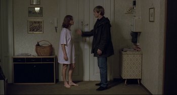 Movie still from “The Piano Teacher” (2001), directed by Michael Haneke – A man and a woman standing next to each other in front of a door; Wide shot, Over the shoulder angle