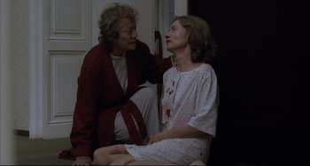 Movie still from “The Piano Teacher” (2001), directed by Michael Haneke – A woman sitting next to another woman with blood on her face; Medium shot, High angle