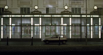 Movie still from “The Piano Teacher” (2001), directed by Michael Haneke – A car driving down a street near a building; Extreme Wide shot, Low angle