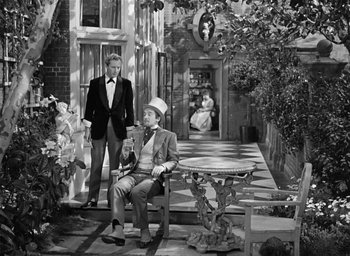 Movie still from “The Picture of Dorian Gray” (1945), directed by Albert Lewin – A man sitting on a chair next to a woman; Wide shot, High angle