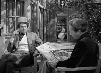 Movie still from “The Picture of Dorian Gray” (1945), directed by Albert Lewin – A man sitting on a chair next to another man holding a magazine; Medium shot, Over the shoulder angle